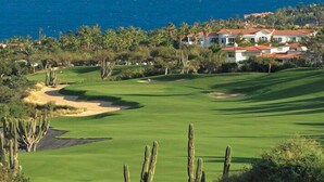 Un parcours de golf offrant une vue sur l’océan, avec des immeubles d’habitation en arrière-plan.
