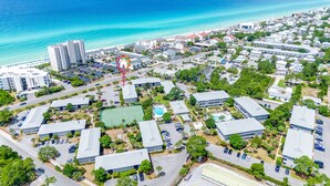 Luchtbeeld van een kustplaats met een strand, woongebouwen en een groot hotelcomplex.