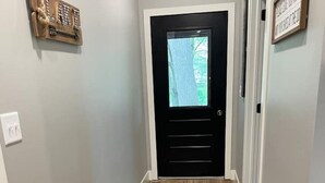 A hallway with a black door, a light switch, and a framed picture on the wall. - Entire Top Floor Only: Okoboji Oasis/ Private Entrance (Arnolds Park)