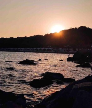 Un atardecer sobre una costa rocosa con agua tranquila.