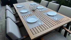 A wooden dining table set with plates, glasses, and a centerpiece.