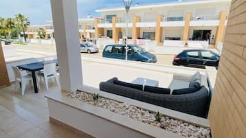 Relax on the balcony with a view of the city street, featuring a seating area with a sofa and a small table.