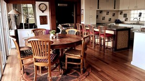 Un coin repas avec une table et des chaises en bois, une cuisine avec des meubles blancs et une grande fenêtre.