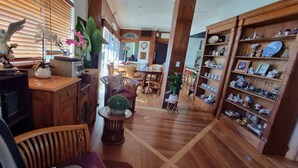 Une pièce spacieuse dotée d’un plancher en bois, d’un coin repas avec des chaises et d’étagères remplies d’objets décoratifs.
