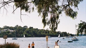 Une plage avec une jetée en bois, des bateaux sur l’eau et un panneau indiquant « Interdiction de plonger ».