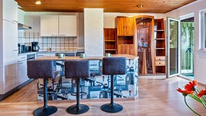 Une cuisine moderne dotée d’un îlot central, de tabourets de bar, de meubles en bois et offrant une vue sur l’extérieur.