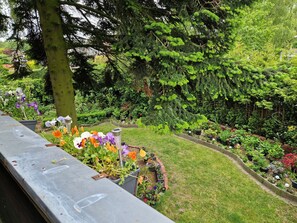 A garden with various plants and flowers, a tree, and a paved area. - Apartment "Klee" with Balcony & Wi-Fi (WHV)