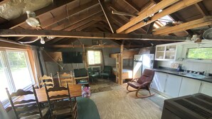A rustic cabin interior with a dining area, a living room, and a kitchen.
