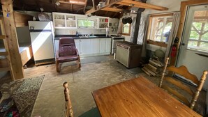 A rustic kitchen with wooden beams, a refrigerator, a sink, and a dining table.