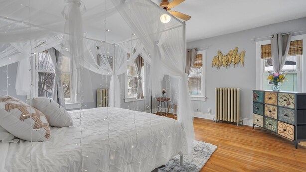 A bedroom with a canopy bed, a radiator, a decorative cabinet, and a view of the outside. - Gorgeous home walking distance to the beach (Rochester)