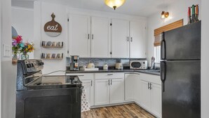 A kitchen with white cabinets, a black refrigerator, a microwave, a toaster, and a coffee maker. - Gorgeous home walking distance to the beach (Rochester)