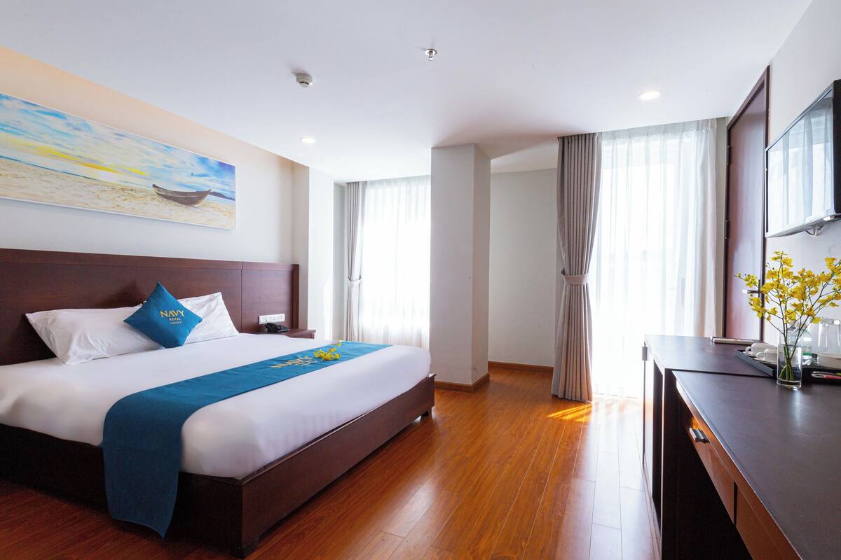 Hotelkamer met een groot bed, een bureau, een televisie en een schilderij aan de muur.