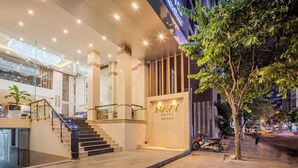 A modern hotel entrance with a staircase, a sign reading "NAVY HOTEL," and a tree on the sidewalk. - Navy Nha Trang Hotel (Nha Trang)
