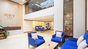 A hotel lobby with a reception desk, blue seating area, and a decorative wall. - Navy Nha Trang Hotel (Nha Trang)