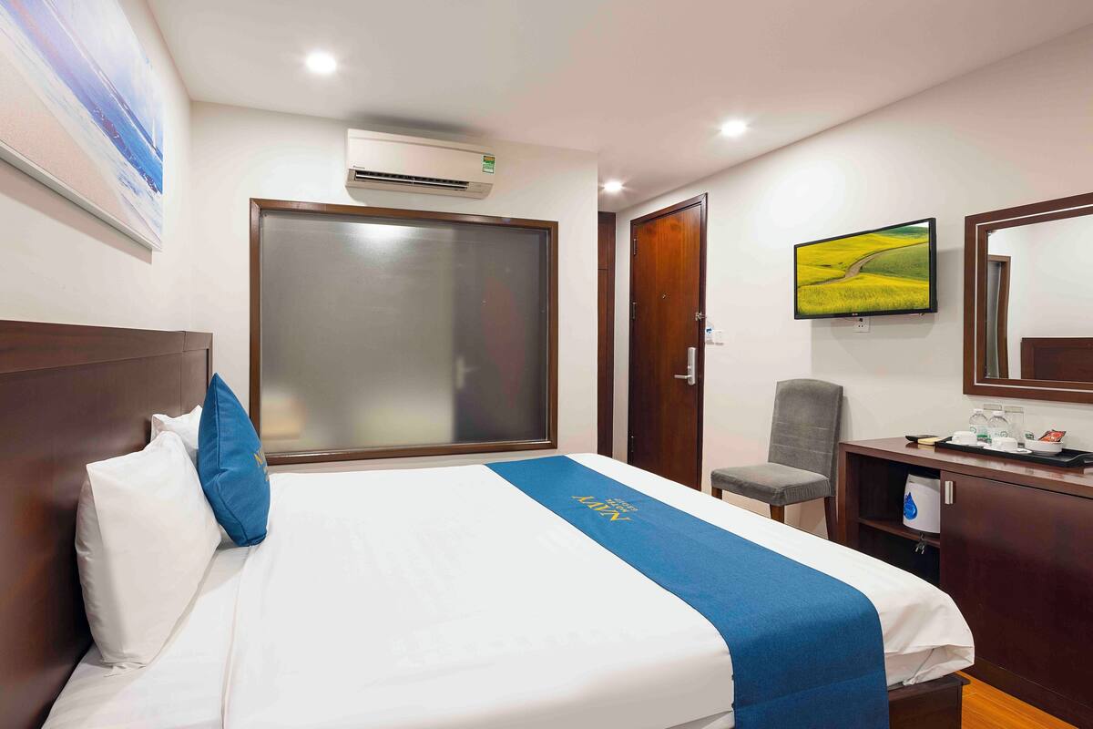Een hotelkamer met een bed, een bureau, een stoel, een televisie en een kledingkast.