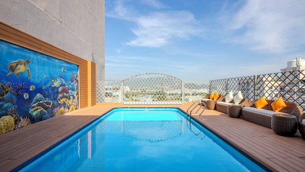 A rooftop pool with a mural of marine life, wooden deck, and outdoor seating area. - Navy Nha Trang Hotel (Nha Trang)