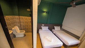 Ein kleines, modernes Zimmer mit zwei Einzelbetten, einer Toilette und einer Dusche.