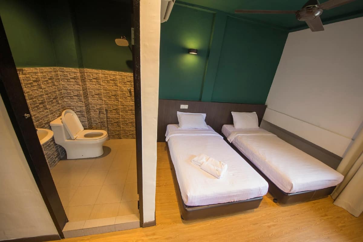 A small, modern room with two single beds, a toilet, and a shower area.