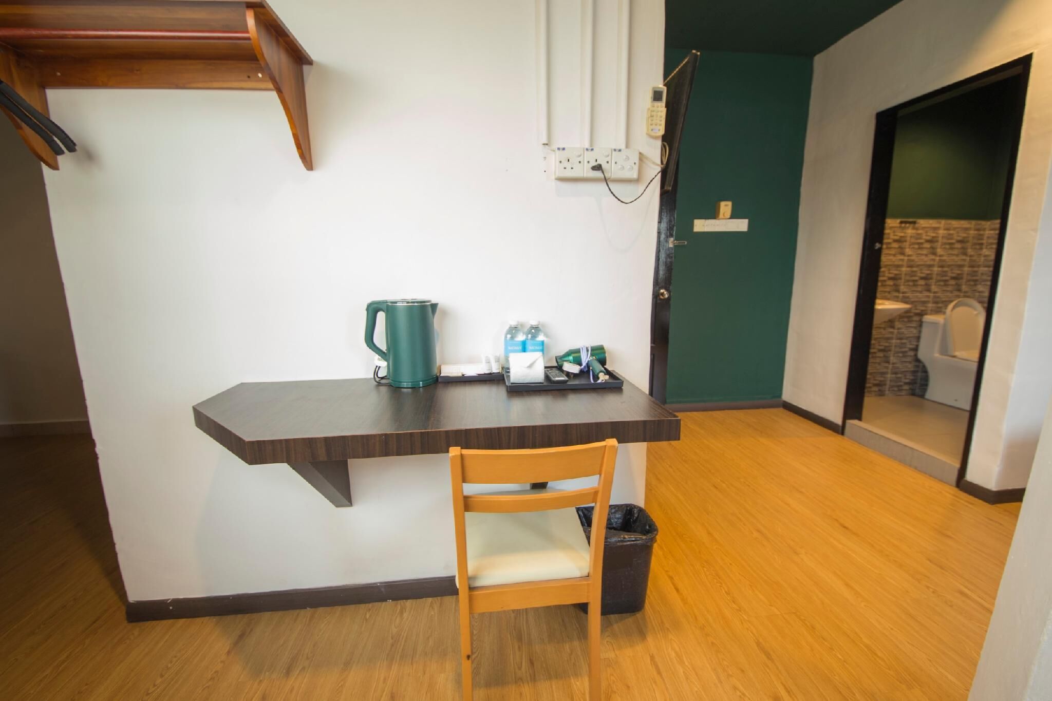 Une petite cuisine équipée avec une table en bois, une bouilloire verte et une chaise.