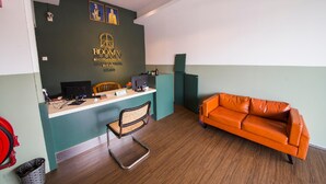 Ein Empfangsschalter mit Computer, Stuhl und einer Couch in der Hotelhalle.