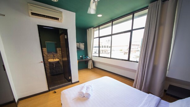 Ein Hotelzimmer mit Bett, Badezimmer mit Waschbecken und einem großen Fenster.