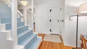 Una escalera con barandillas blancas y escalones azules que conduce a una puerta con manijas negras.