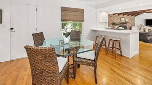 Cocina moderna con una isla central, muebles blancos y una pared de ladrillo decorativa.