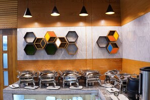Een buffetopstelling met verschillende bedieningspunten, zeshoekige wanddecoraties en hanglampen.