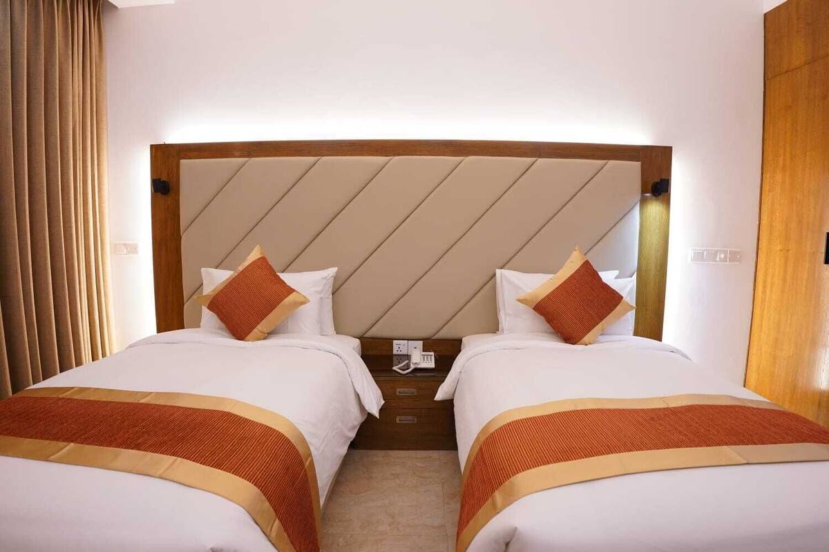 A hotel room with two beds, a wooden headboard, and a telephone on the nightstand.