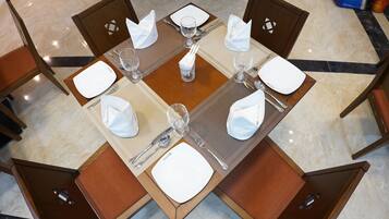 A dining table set for four with a square placemat, white napkins, and silverware.