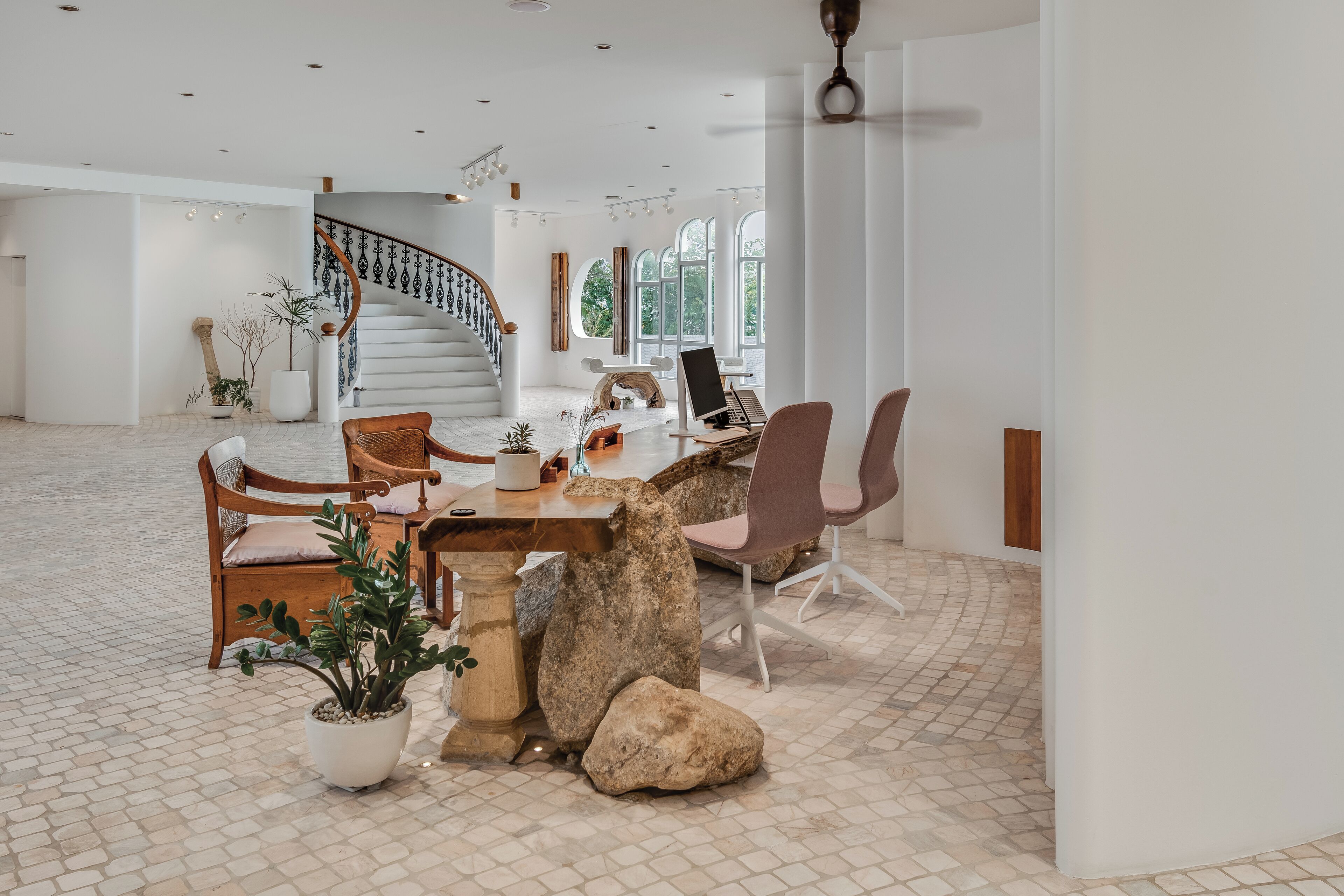 Una habitación amplia con una escalera moderna, un comedor con mesa y sillas, y un gran ventanal que proporciona luz natural.