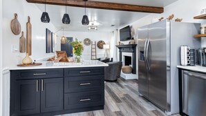 Una cocina moderna con gabinetes negros, un refrigerador de acero inoxidable y una viga de techo de madera.
