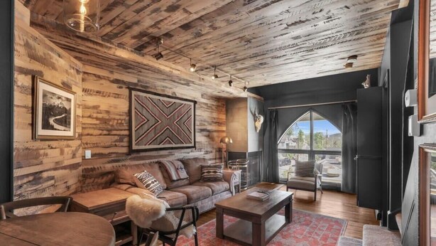 A rustic interior with a wooden ceiling, a large framed artwork, a sofa, a coffee table, and a view through a window. - Downtown 3BR Park City Retreat: Walk to Town Lift (Park City)