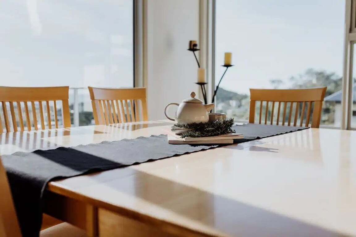 A dining table with chairs, a teapot, candles, and a book.