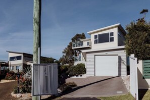 Un edificio residenziale a due piani con garage, balcone e giardino recintato.