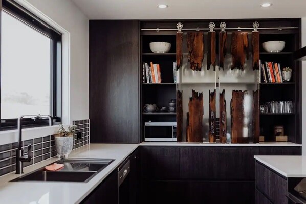 Une cuisine moderne avec des meubles de couleur bois foncé, un plan de travail noir et une fenêtre.