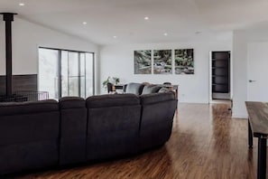 A modern living room with a sectional sofa, a fireplace, and a large window with a view of trees.