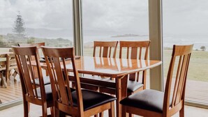A dining table with chairs and a large window with a view of the outdoors. - OceanFront - Absolute Waterfront (Glamorgan-Spring Bay)