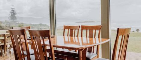 A dining table with chairs and a large window with a view of the outdoors.