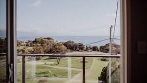A view from a window overlooking a grassy area with trees and a road. - Haven on James - Luxurious Ocean Vista (Glamorgan-Spring Bay)