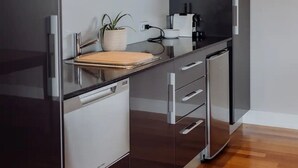 A modern kitchen with dark cabinetry, a wooden countertop, and a built-in dishwasher. - Haven on James - Luxurious Ocean Vista (Glamorgan-Spring Bay)