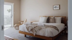 A bedroom with a bed, a chair, a window, and a framed picture on the wall. - Haven on James - Luxurious Ocean Vista (Glamorgan-Spring Bay)