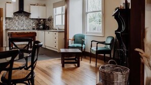 Un soggiorno spazioso con pavimento in legno, un pianoforte e un'area pranzo con tavolo e sedie in legno.