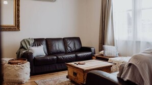 Un soggiorno con un divano in pelle scura, un tavolino in legno e un tappeto decorato.