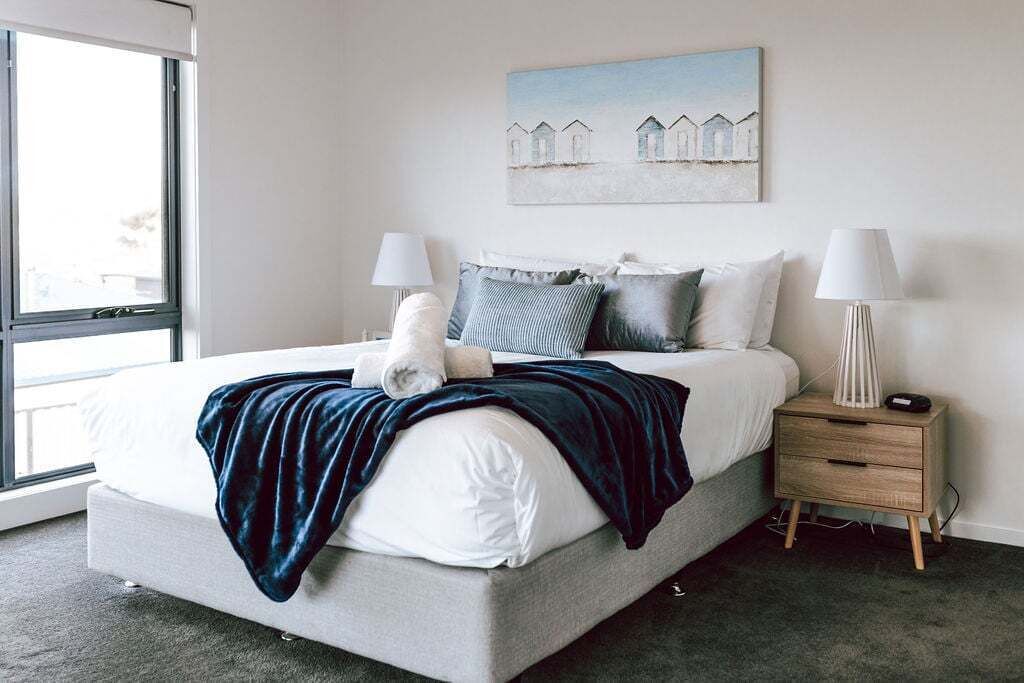 A modern bedroom with a large bed, two bedside tables, and a window.