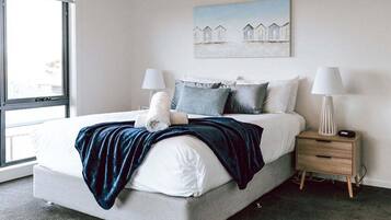 A modern bedroom with a large bed, two bedside tables, and a window.