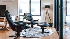 A modern living room with leather chairs, a small table, and a floor lamp. - Anchored@Bicheno - Ohmyview! (Glamorgan-Spring Bay)