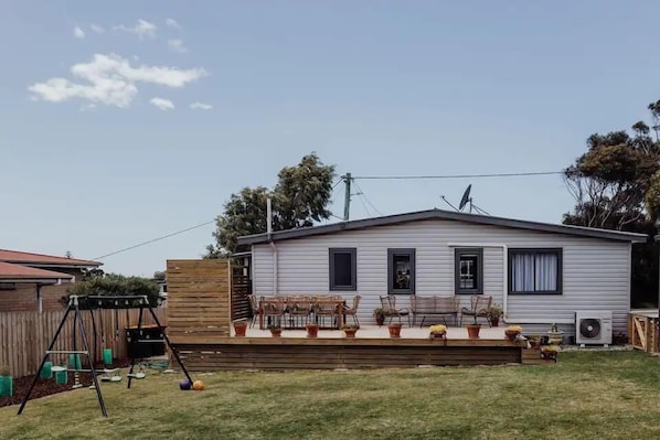 A single-story mobile home with a patio area, outdoor seating, and a swing set. - BASK at Bicheno - Cute Two Bedroom Getaway (Bicheno)