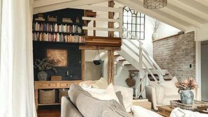 A spacious living area with a large sofa, a staircase, and a bookshelf filled with books.