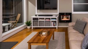 A modern living room with a flat-screen TV, a wooden coffee table, a sofa, and a fireplace.